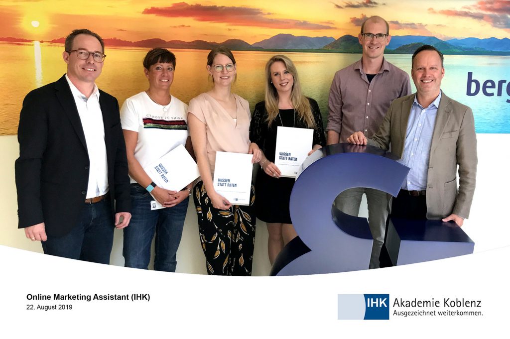 Online Marketing Assistant Teilnehmende halten Zertifikat in der Hand und posieren für die Kamera